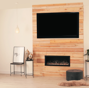 Een moderne woonkamer heeft een houten accentmuur met een flatscreen-tv boven een open haard. Aan de ene kant staat een stoel met een minimalistische ingelijste schildersprint, decoratieve vazen op twee bijzettafels, een hangende hanglamp, een zwarte ottomane en een harige vloerkleed op de vloer.