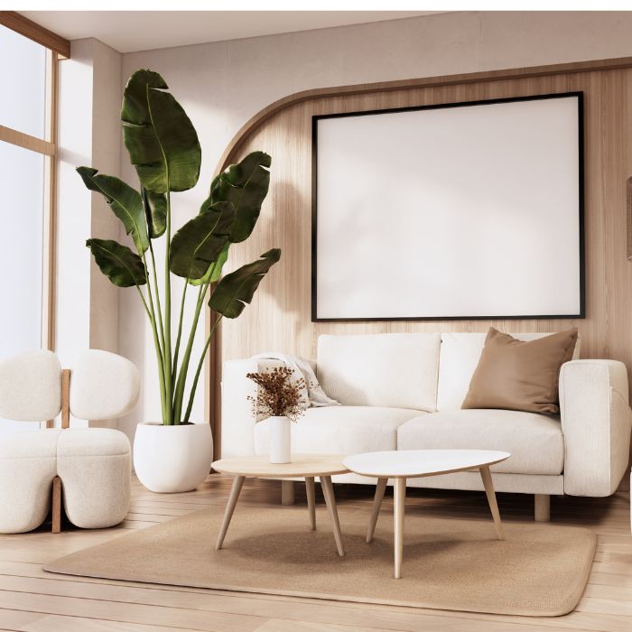 Een moderne woonkamer met een beige kleurenpalet, met een witte bank versierd met beige kussens, een grote potplant met brede bladeren, een paar ronde witte stoelen en een in elkaar passende salontafel op een beige kleed onder een leeg fotolijstje van de bekende schilders aan de muur. Een moderne woonkamer met een beige kleurenpalet, met een witte bank versierd met beige kussens, een grote potplant met brede bladeren, een paar ronde witte stoelen en een in elkaar passende salontafel op een beige kleed onder een leeg fotolijstje van de bekende schilders aan de muur.
