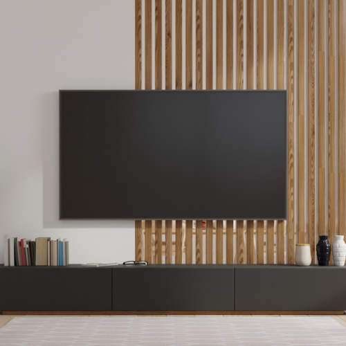 Een moderne woonkamer heeft een grote flatscreen-tv die aan een muur met verticale houten latten is bevestigd. Onder de tv staat een lage, zwarte mediaconsole met verschillende boeken en decoratieve objecten zoals vazen die netjes op de bovenkant zijn gerangschikt. Op de vloer ligt een wit kleed.